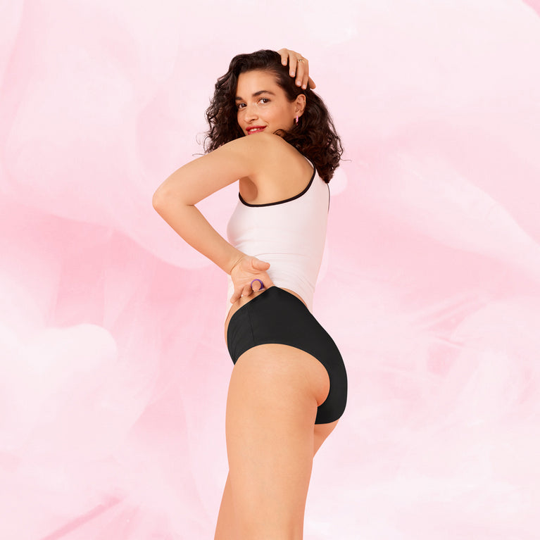 Femme portant un tank top blanc et le ComfortFit Essentielle Hipster Moderate, offrant une protection menstruelle fiable et ajustée, idéale pour un confort quotidien.