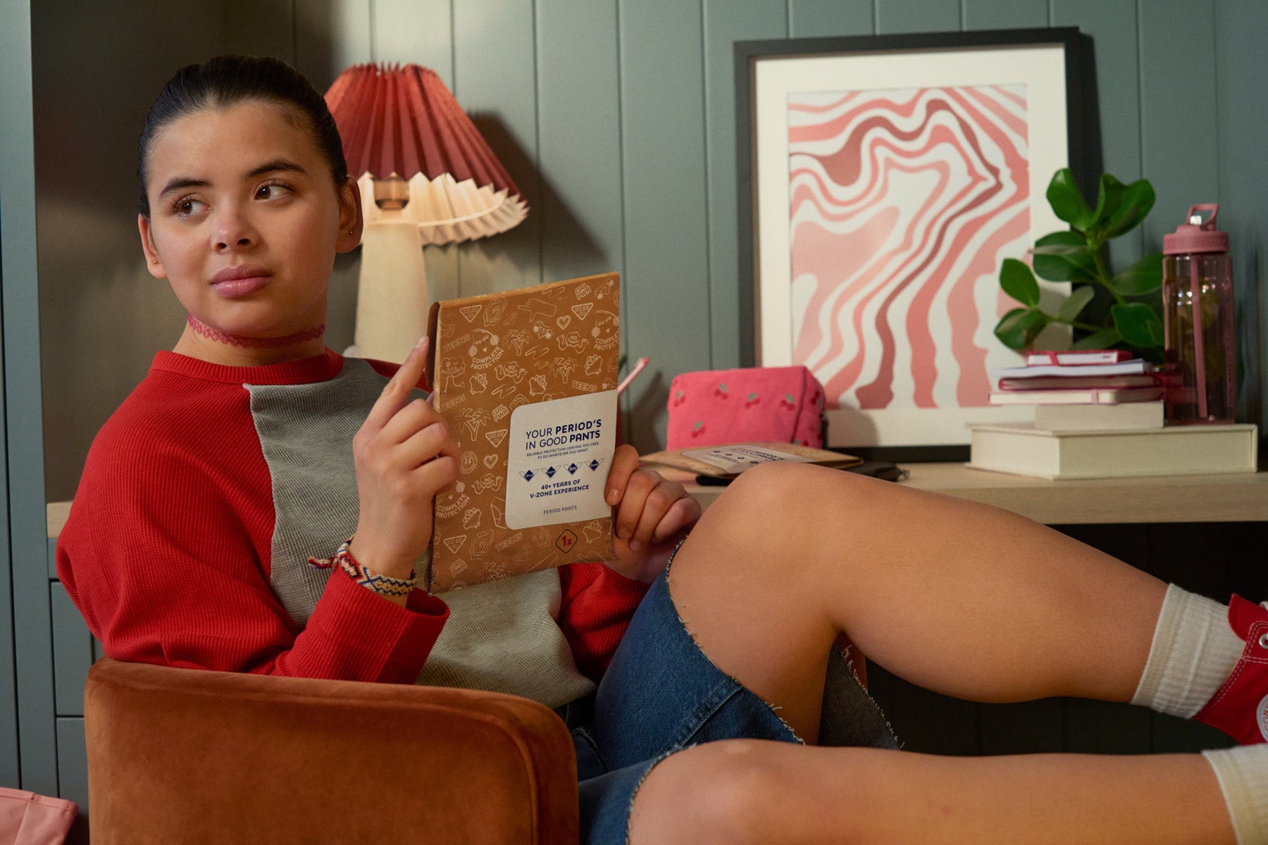 Alt text: Femme assise dans un fauteuil tenant dans ses mains une culotte menstruelle Nana encore dans son emballage