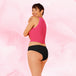 Femme en débardeur rose mettant en valeur la culotte menstruelle ComfortFit Essentielle Brazilian, offrant protection fiable et confort grâce à la technologie TriTech Performance.