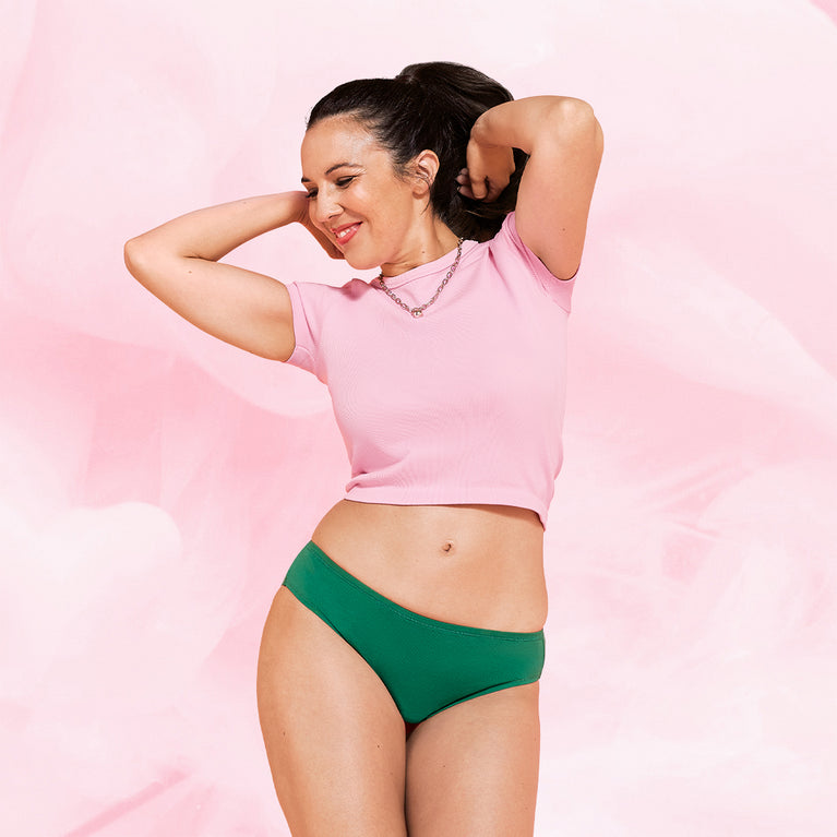 Femme portant la culotte menstruelle ComfortFit Essentielle Brazilian Heavy, taille haute, offrant protection discrète et fiable grâce à la technologie TriTech Performance et gousset ComfortFit ajusté.