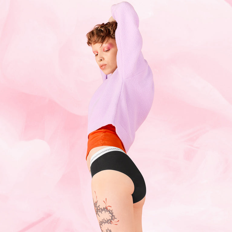 Femme portant la culotte menstruelle ComfortFit Essentielle Hipster Logo Moderate, offrant protection discrète et fiable, adaptée pour un flux léger, avec coupe hipster confortable.