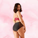 Femme souriante portant la culotte menstruelle taille haute High Waist Dots Light avec détails en dentelle à pois, offrant confort et absorption pour flux léger.