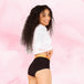 Femme souriante portant les culottes menstruelles Ados - Brief Logo Waistband Moderate, avec taille haute et ceinture motifs « Fearless », conçues pour confort et protection.