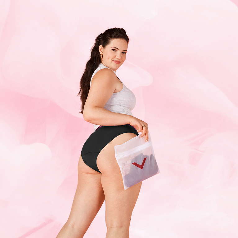 Une femme tient un filet à linge Nana, idéal pour protéger et laver délicatement les sous-vêtements menstruels, préservant leur qualité et durabilité.