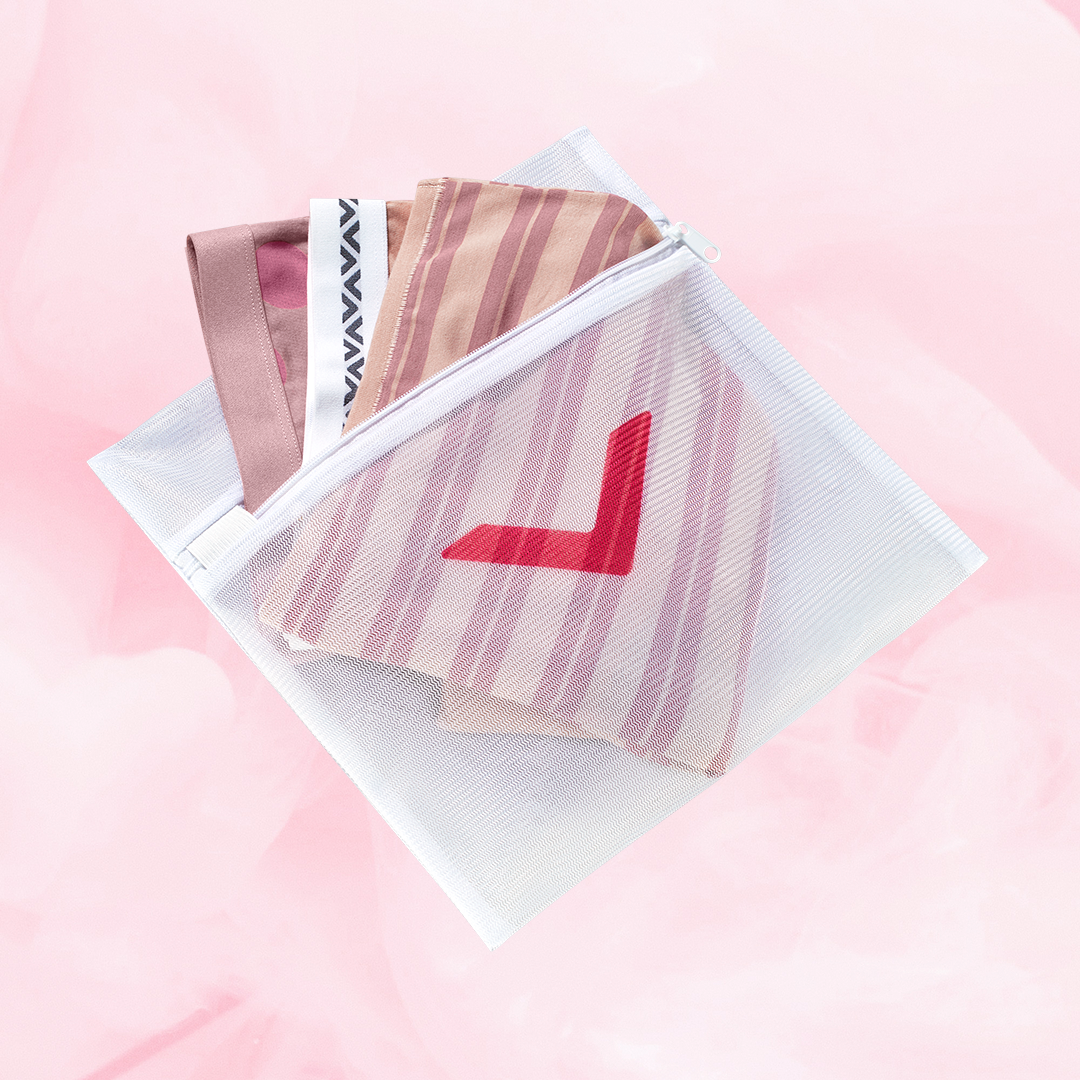 Filet à linge blanc avec flèche rouge, conçu pour protéger et laver délicatement les sous-vêtements menstruels, équipé d'une fermeture éclair pour sécuriser le contenu.