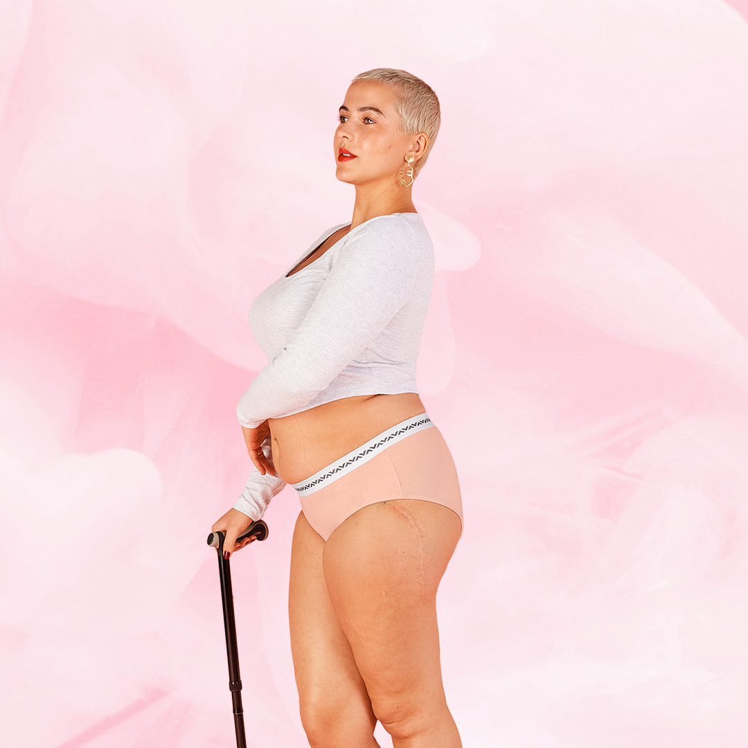 Femme en sous-vêtement ComfortFit Essentielle Hipster Logo Moderate, tenant une canne, mettant en valeur le design ajusté et la protection discrète.