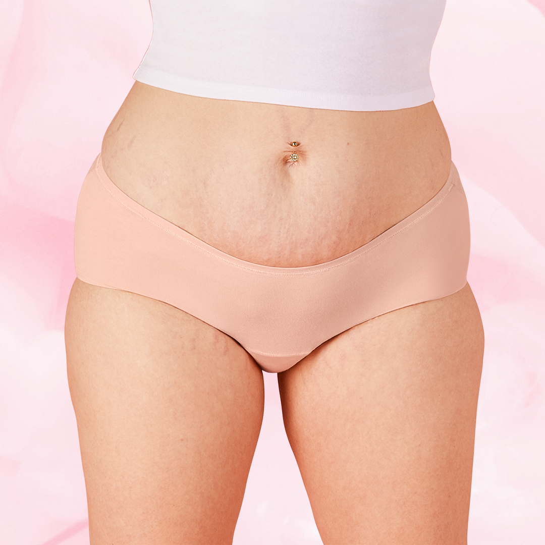Gros plan sur le ventre d'une femme portant la culotte menstruelle ComfortFit Essentielle Hipster, offrant protection fiable et discrète pour flux léger.