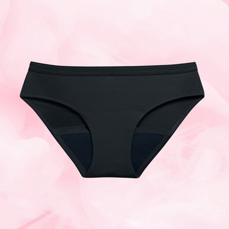 Culotte menstruelle noire du Pack Back to Basics, modèle Bikini pour flux modérés, sur fond rose. Design simple, intégrable à toute garde-robe.